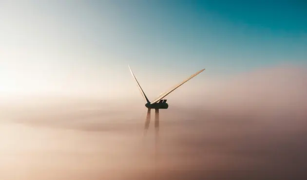 A wind turbine partially obscured by mist